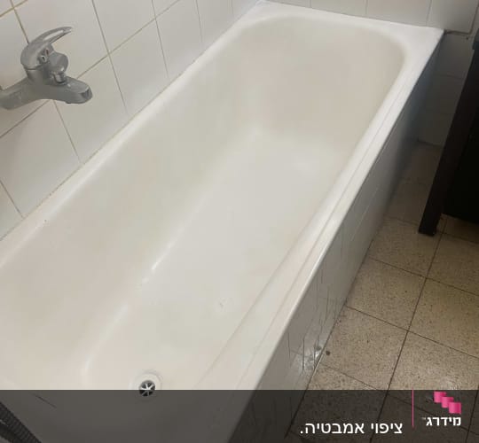 אמבטיה לבנה עם ברז מתכת על קיר אריחים